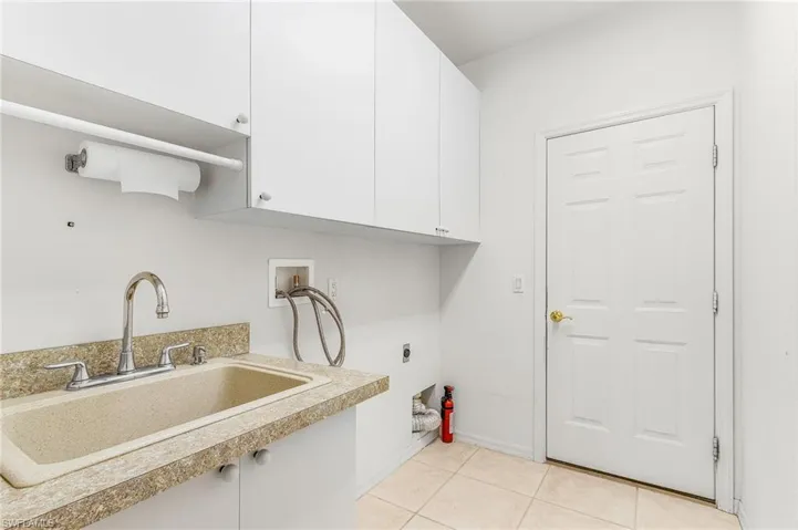 Laundry area with cabinet space, hookup for a washing machine, electric dryer hookup, and light tile patterned flooring
