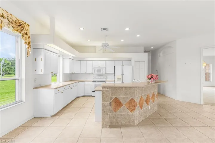 Kitchen with white appliances, light countertops, healthy amount of natural light, light tile patterned floors, and recessed lighting