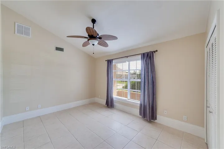 Guest Bedroom #1, Unfurnished bedroom with light tile patterned floors, lofted ceiling, ceiling fan, and a closet