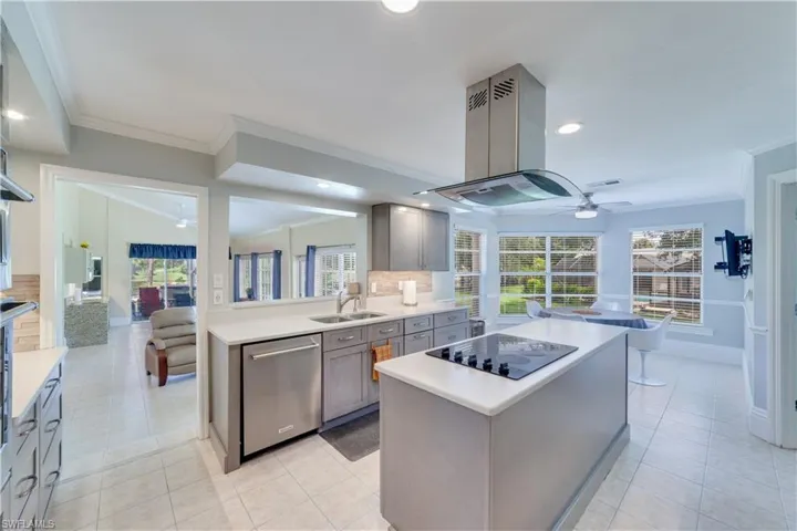 Kitchen featuring built in fridge, a center island, ceiling fan, black electric stovetop, and sink