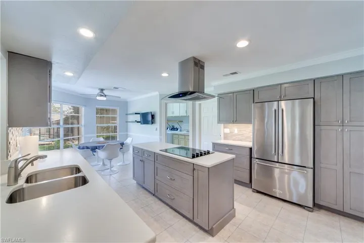 Kitchen featuring appliances with stainless steel finishes, tasteful backsplash, island exhaust hood, beverage cooler, and sink