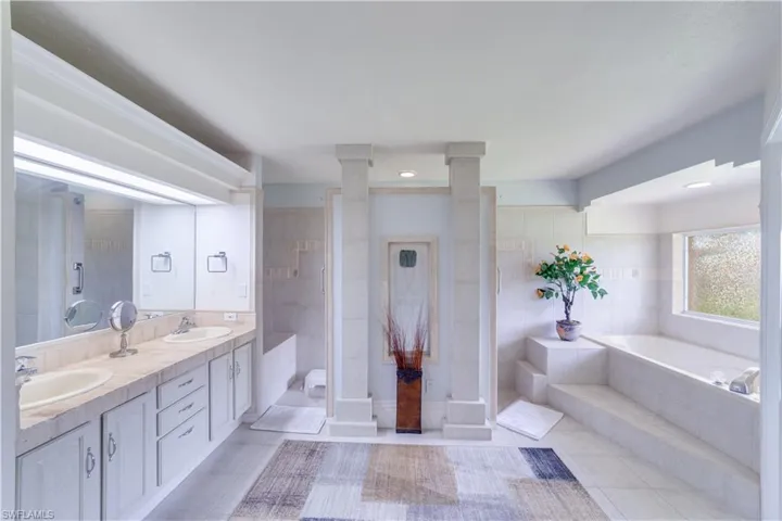 Bathroom featuring tile walls, shower with separate bathtub, tile patterned floors, vanity, and ornate columns
