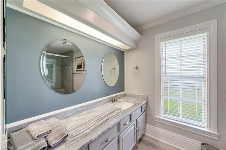 Bathroom featuring hardwood / wood-style floors, a shower with door, vanity, and crown molding