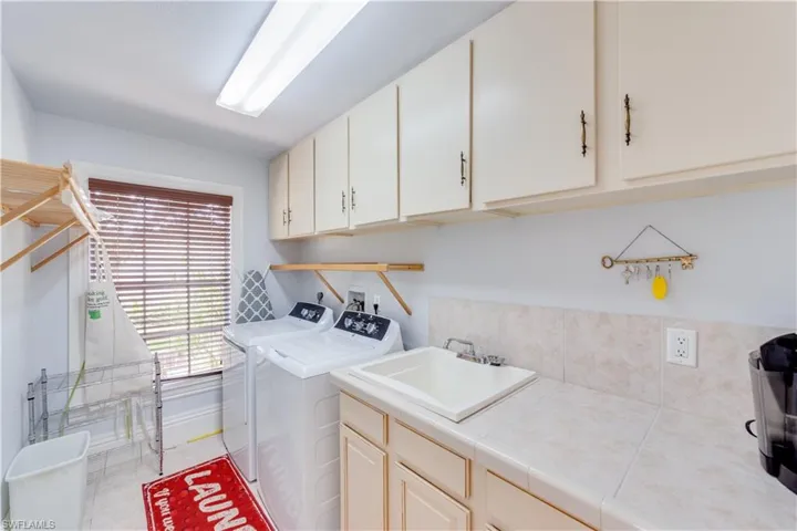 Laundry area featuring separate washer and dryer, cabinets, and sink