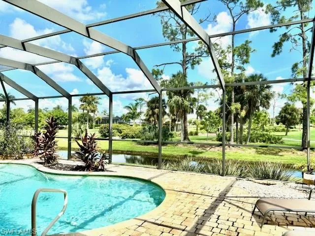 View of pool with screen enclosure, a water view, and a patio area