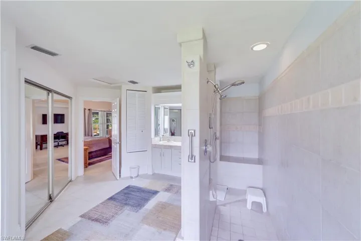 Master Bathroom with tiled walk-thru shower, vanity, and tile patterned floors