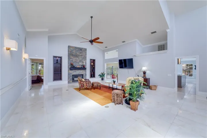 Living room featuring light tile patterned floors, ceiling fan, a skylight, and high vaulted ceiling