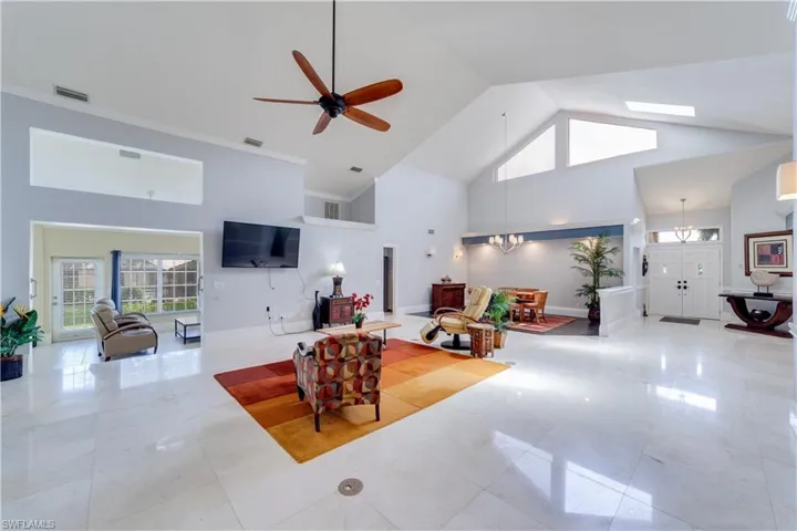 featuring high vaulted ceiling, ornamental molding, ceiling fan, and a fireplace