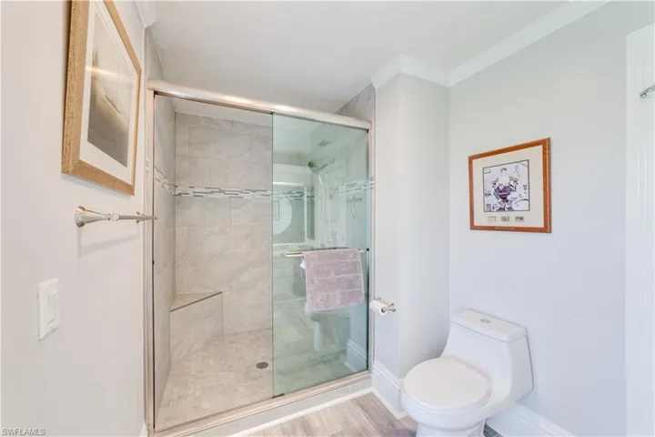 Bathroom featuring crown molding, walk in shower, hardwood / wood-style floors, and toilet