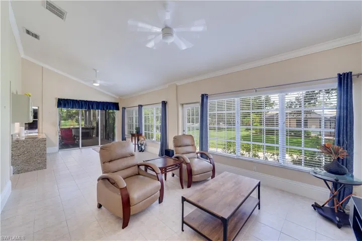 Huge Tiled Family room with ornamental molding, ceiling fan, high vaulted ceiling, and a healthy amount of sunlight