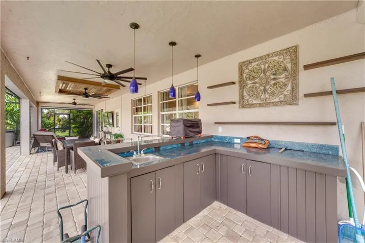 Kitchen featuring ceiling fan, pendant lighting, sink, kitchen peninsula, and gray cabinetry