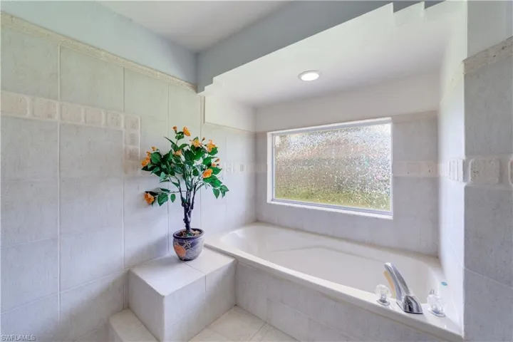 Master Bathroom with tile walls, tiled bath, and tile patterned floors