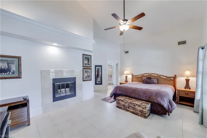 Master Bedroom with a tile fireplace, light tile patterned floors, ceiling fan, and high vaulted ceiling