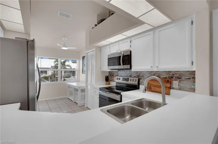 Kitchen with white cabinets, appliances with stainless steel finishes, light countertops, and tasteful backsplash