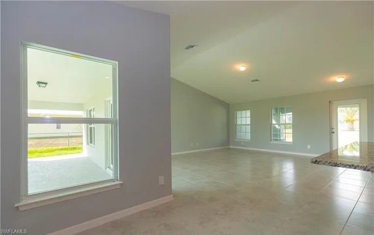 Unfurnished room featuring vaulted ceiling and light tile patterned flooring