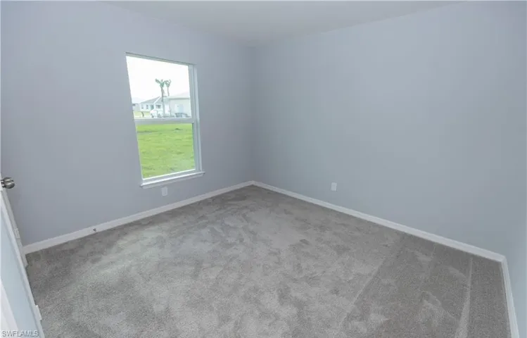 Empty room featuring baseboards and light carpet