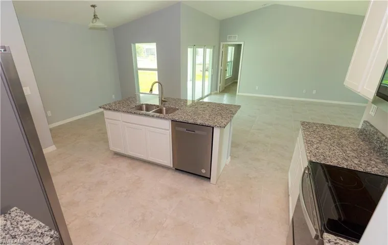 Kitchen with electric stove, open floor plan, white cabinetry, light stone countertops, and stainless steel dishwasher