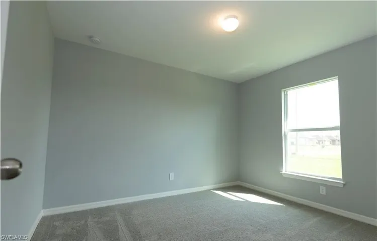 Carpeted empty room featuring baseboards