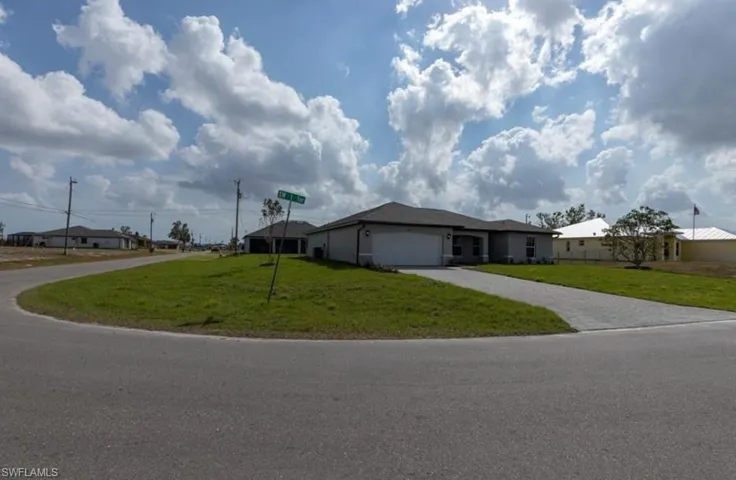 Ranch-style home featuring a front lawn, decorative driveway, a garage, and a residential view