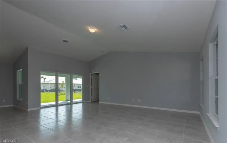 Spare room with lofted ceiling and light tile patterned floors
