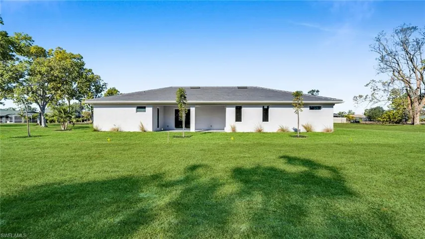 Rear view of property with a lawn, a patio area, and stucco siding