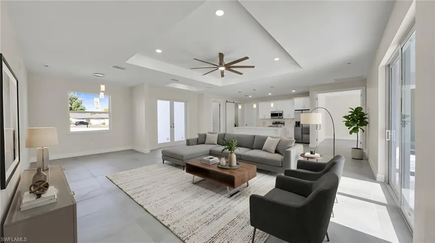 Living room featuring recessed lighting, ceiling fan, a raised ceiling, and french doors