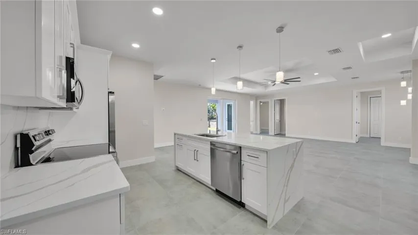 Kitchen featuring white cabinetry, light stone countertops, ceiling fan, stainless steel appliances, and recessed lighting