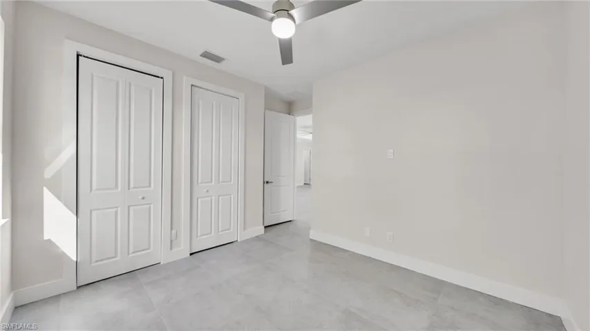 Unfurnished bedroom with a ceiling fan and multiple closets
