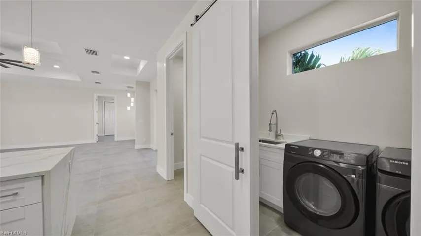 Washroom with a barn door, recessed lighting, independent washer and dryer, and a raised ceiling