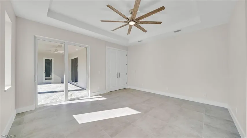 Unfurnished bedroom with ceiling fan and a tray ceiling