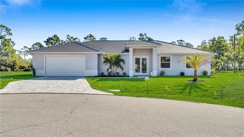 View of front of home with a front yard, driveway, an attached garage, and a tile roof