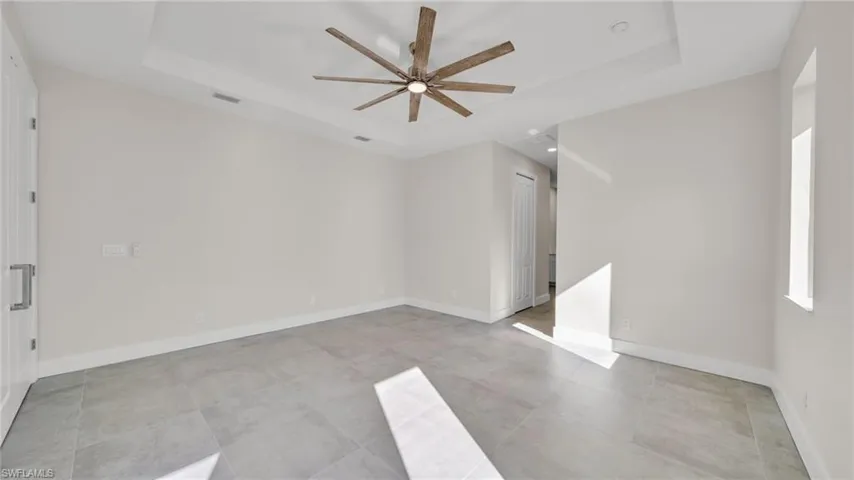 Unfurnished room featuring ceiling fan and a tray ceiling