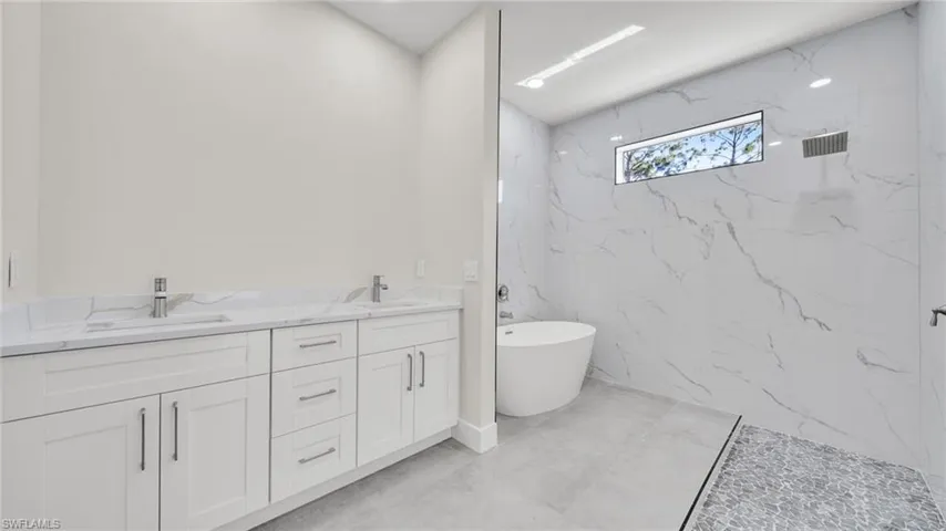 Full bathroom with double vanity, a freestanding bath, and a marble finish shower