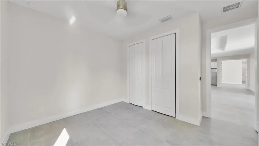 Unfurnished bedroom featuring multiple closets, high quality fridge, a ceiling fan, and light tile patterned floors