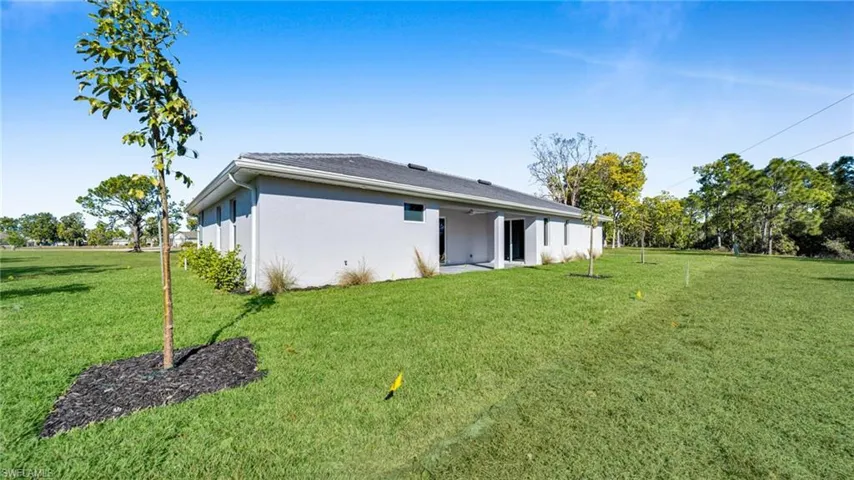 Back of property with a patio, a lawn, and stucco siding