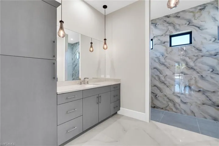 Bathroom with a marble finish shower, vanity, and light marble finish floors