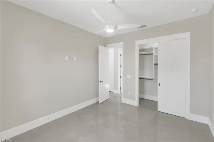 Unfurnished bedroom with a closet, ceiling fan, and concrete floors