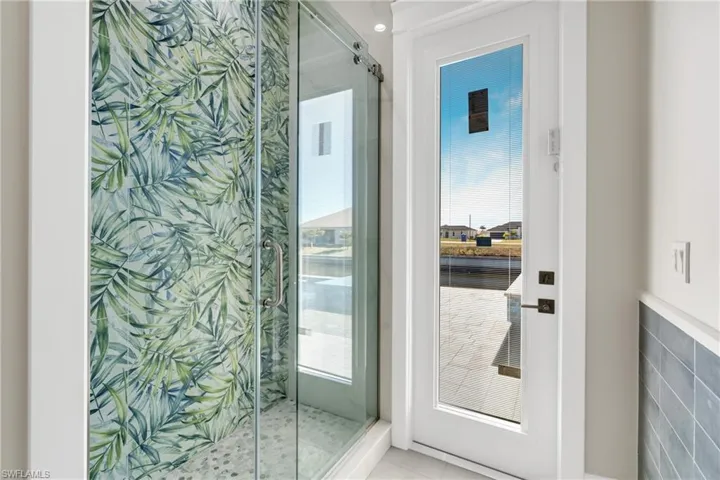 Bathroom featuring a shower stall, healthy amount of natural light, and tile walls