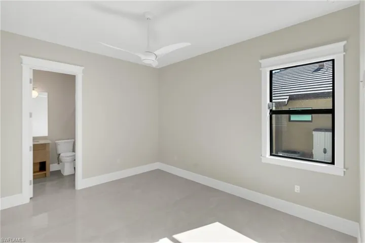 Unfurnished bedroom featuring ceiling fan and connected bathroom