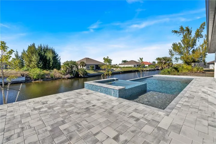 View of swimming pool featuring a water view, a patio area, a pool with connected hot tub, and a residential view