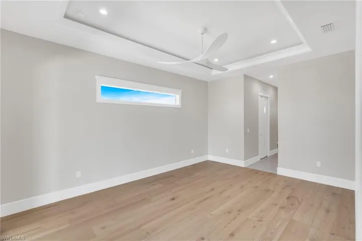 Spare room with a raised ceiling, recessed lighting, light wood-style floors, and a ceiling fan