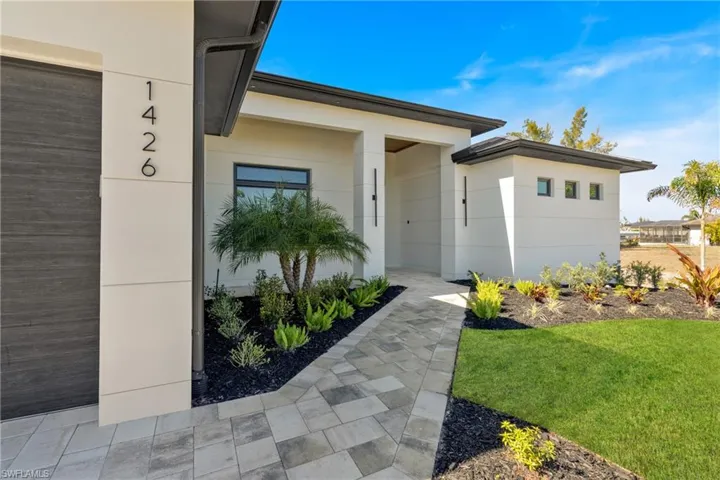Doorway to property with a lawn and stucco siding