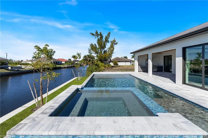 View of swimming pool featuring a patio area, a water view, and a pool with connected hot tub