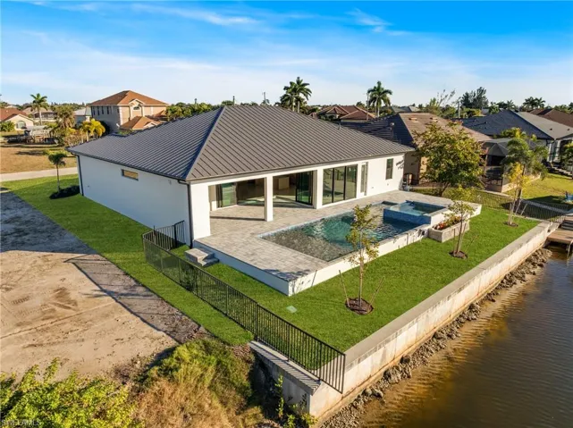 Rear view of house featuring a patio, a fenced backyard, a residential view, a metal roof, and stucco siding