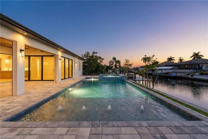 Pool at dusk with a pool with connected hot tub and a patio area