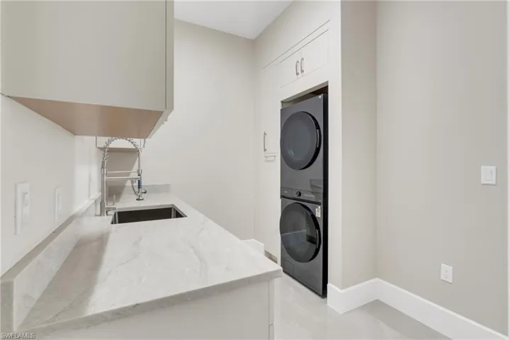 Laundry room featuring stacked washer / drying machine and baseboards