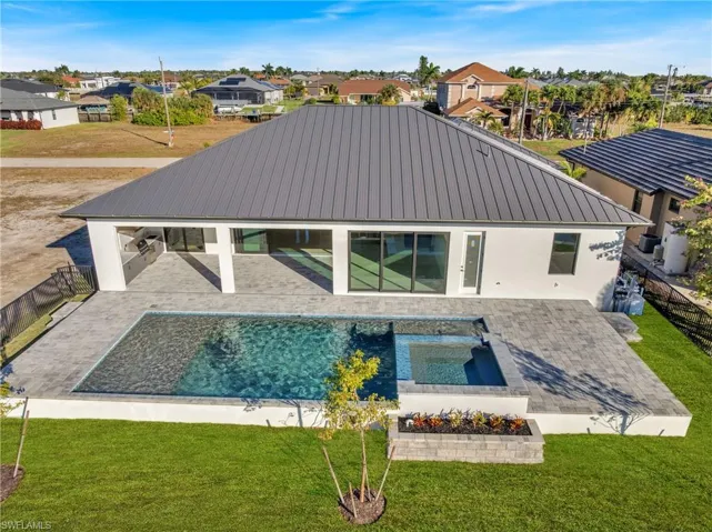 Rear view of house with a fenced backyard, a metal roof, a patio area, and stucco siding