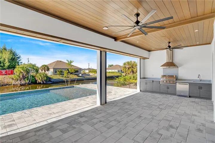 View of patio featuring area for grilling, a ceiling fan, a residential view, a water view, and an outdoor pool