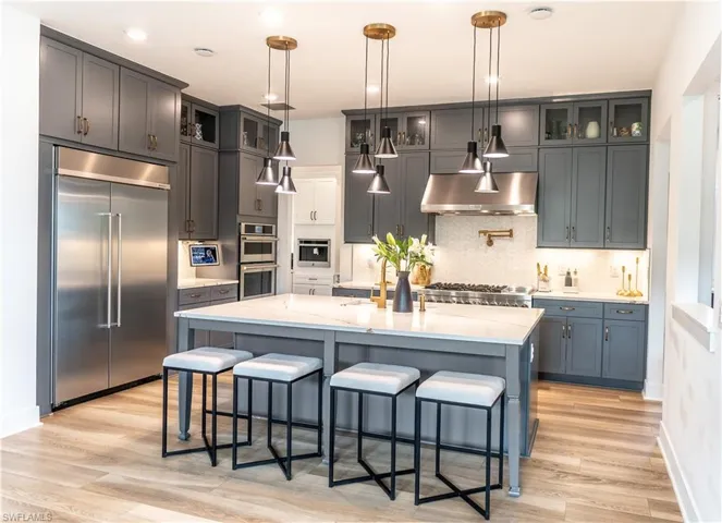 Spacious kitchen featuring gray cabinetry, a large kitchen island with a light-toned countertop, and stainless steel appliances