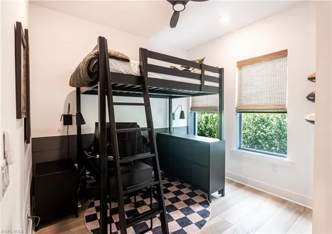 Firstfloor bedroom featuring a built-in loft bed with integrated ladder, light wood-finish flooring, recessed lighting, and a ceiling fan